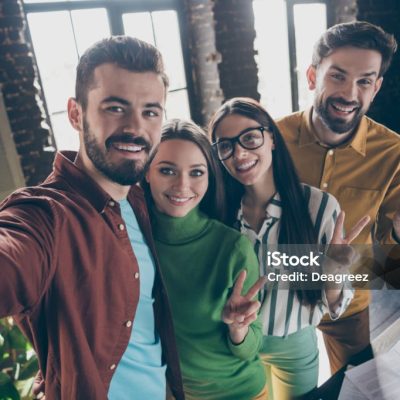 Self-portrait of four nice attractive friendly glad cheerful cheery professional people partners showing v-sign having fun day, at industrial loft interior style workplace workstation office