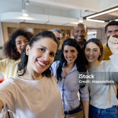 Successful group of Latin American business people at the office celebrating an achievement and looking at the camera smiling